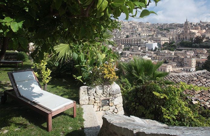 Elegant stone-walled boutique hotel nestled in scenic Sicilian landscape, with rustic terrace overlooking historic Modica's sun-drenched architectural charm