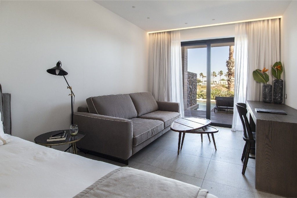 Minimalist white deluxe suite with elegant design, private balcony, and shared azure pool overlooking scenic Greek coastal landscape at Lango Design Hotel & Spa