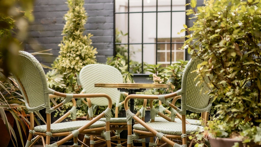 Elegant garden terrace suite with plush king bed, contemporary UK design, soft neutral tones, and expansive windows overlooking lush private garden landscape