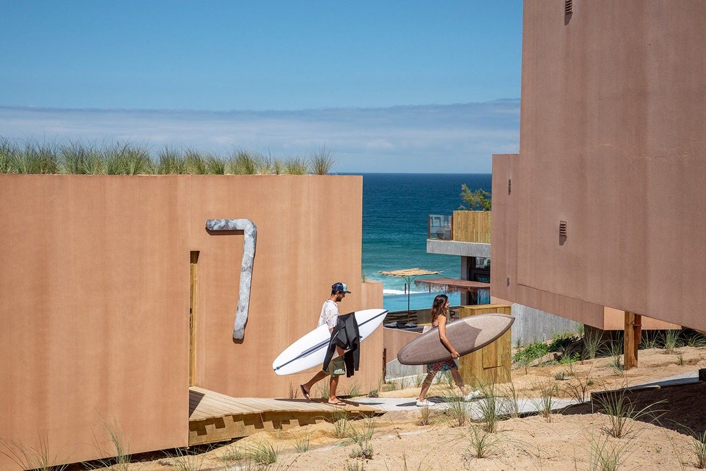 Minimalist wood-paneled bungalow with ocean view, sleek design featuring panoramic windows overlooking coastal landscape in Portuguese surf retreat