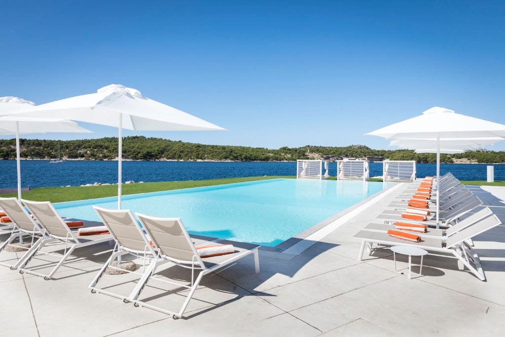 Luxurious waterfront resort with modern architecture overlooking azure Adriatic Sea, nestled among rocky Croatian coastline with sleek white buildings