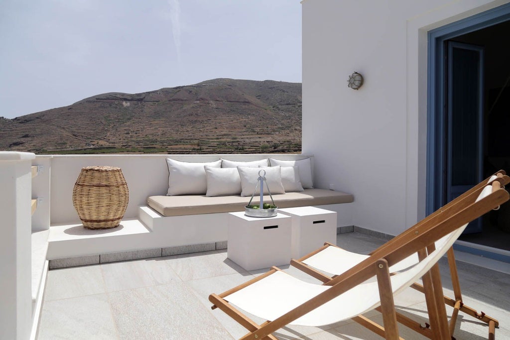 Luxurious white-washed Greek villa with blue-domed roofs overlooking the stunning Aegean Sea, nestled in the picturesque landscape of a traditional Cycladic village