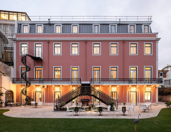 Elegant white palace-style hotel with ornate balconies, set against lush gardens and featuring classical Portuguese architecture