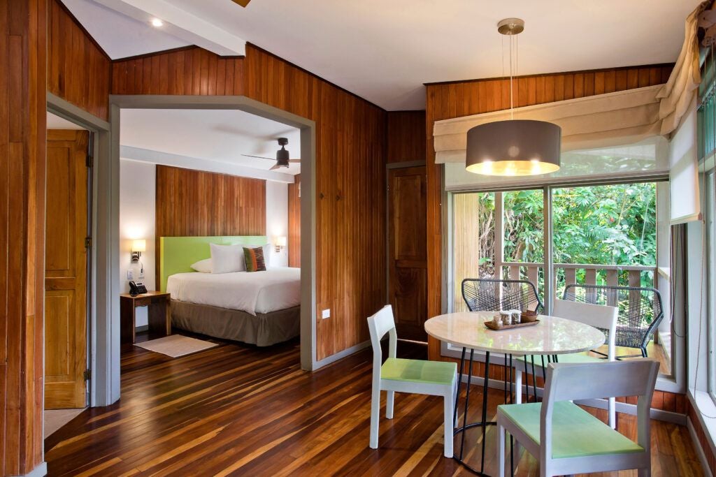 Elegant junior suite at Senda Monteverde Hotel with modern wooden furnishings, plush bedding, and expansive forest views in Costa Rica's lush landscape.