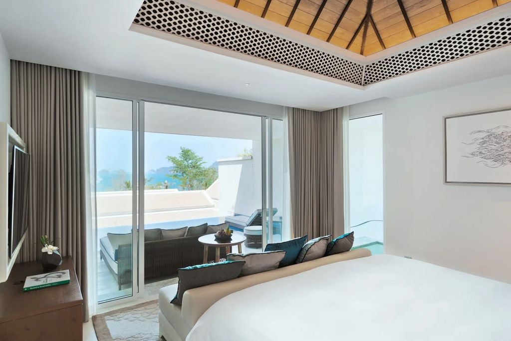 Spacious luxury suite with private infinity pool overlooking partial ocean views, king bed and modern Thai-inspired decor at dusk