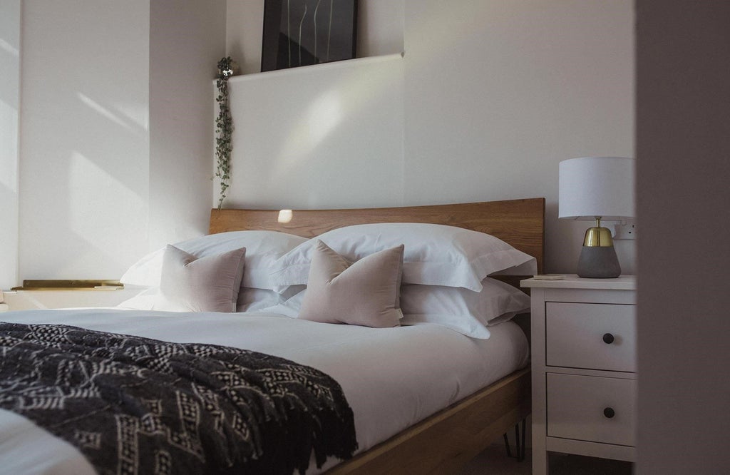 Elegant coastal-inspired hotel room with plush white bedding, ocean-view window, soft neutral tones, and contemporary seaside decor in United Kingdom