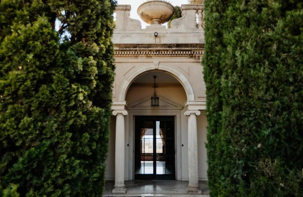 Elegant marble lobby of Grand Hotel with crystal chandeliers, plush seating, and panoramic views of Barcelona's historic cityscape through large windows