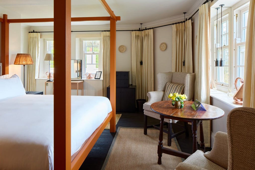 Elegant boutique hotel room with plush white bedding, soft neutral tones, antique furniture, and warm wooden accents at Grove of Narberth countryside retreat