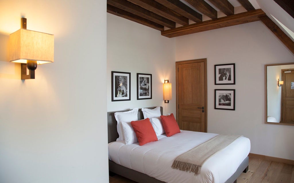 Elegant French country hotel room with soft beige walls, antique wooden furniture, and pristine white linens at Manoir de Surville