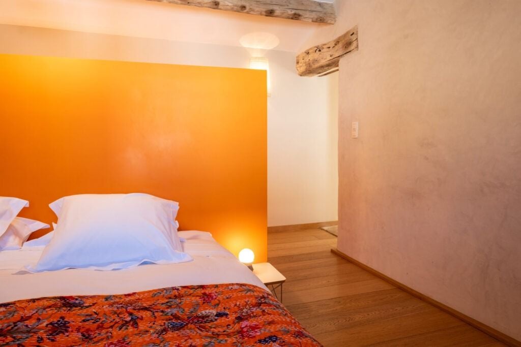 Elegant stone-walled suite with soft white linens, antique furniture, and large windows overlooking lavender fields in a charming French countryside hotel