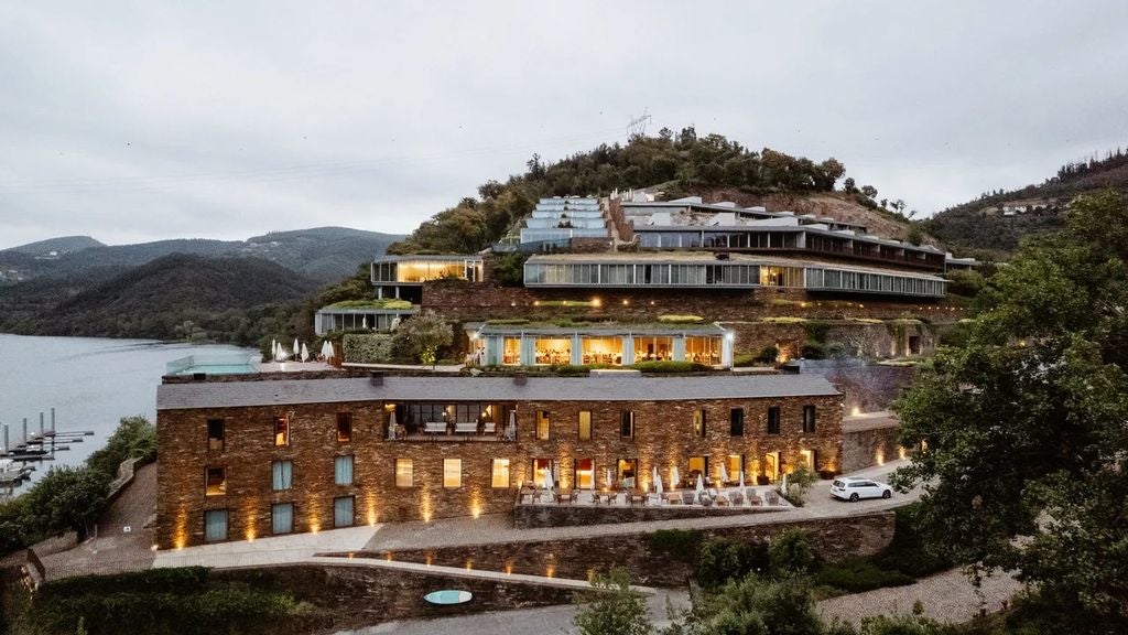 Luxurious infinity pool overlooking the terraced vineyards and winding Douro River valley at sunset, with modern loungers and umbrellas