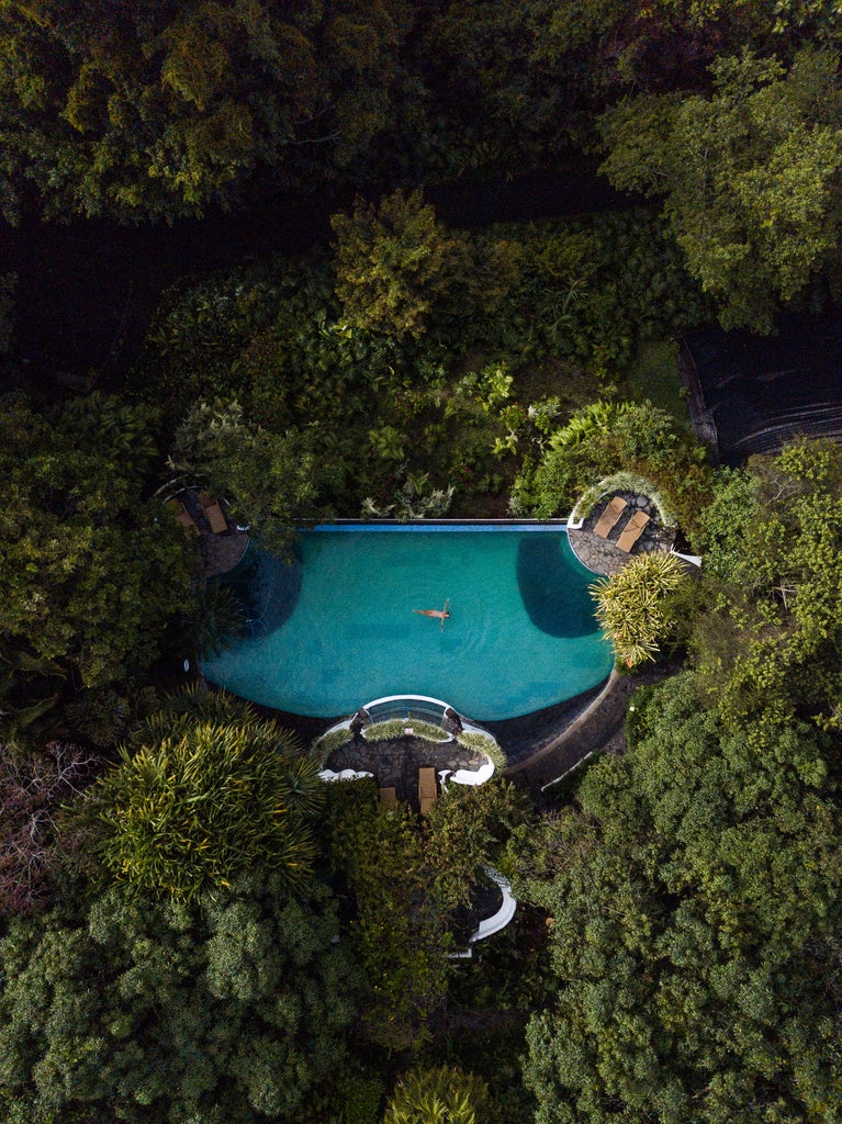 Elegant white-walled luxury inn nestled in lush Costa Rican coffee plantation with tropical gardens and mountain views at sunset