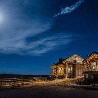 Rustic wooden lodge bedroom with western-inspired decor, plush bed, large windows overlooking scenic mountain landscape at Scenset Mountain Ranch