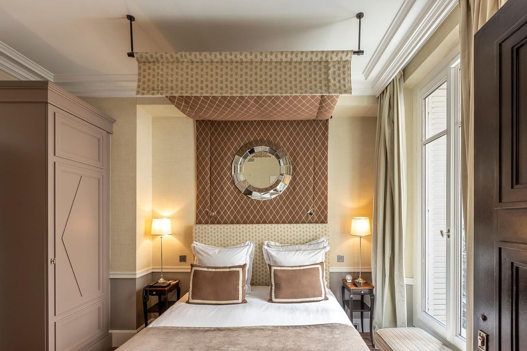 Elegant Parisian hotel room with soft neutral tones, plush white bedding, classic French design, and refined architectural details in warm light