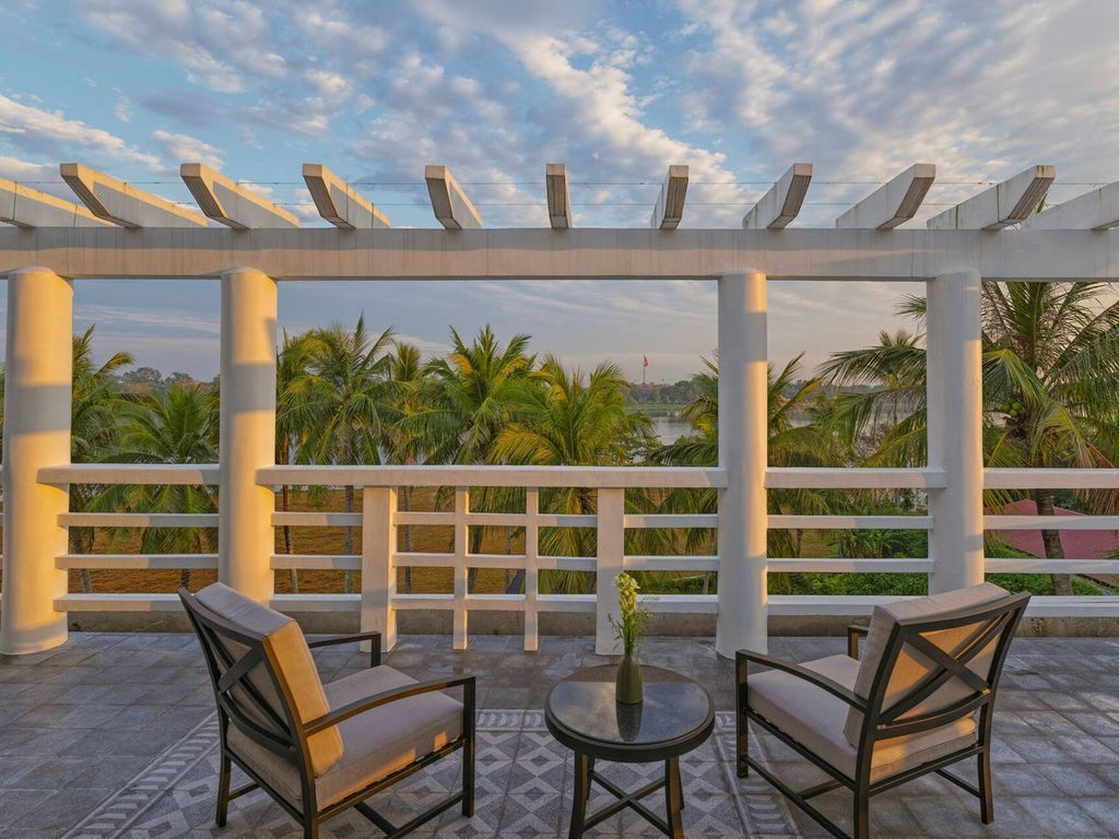 Elegant Perfume River Suite at Azerai La Residence, featuring colonial-style decor, river view, luxurious king bed, and warm Vietnamese design elements