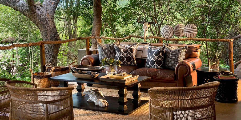 Luxury safari lodge suite with private plunge pool overlooking African savanna, featuring thatched roof and wooden deck terrace