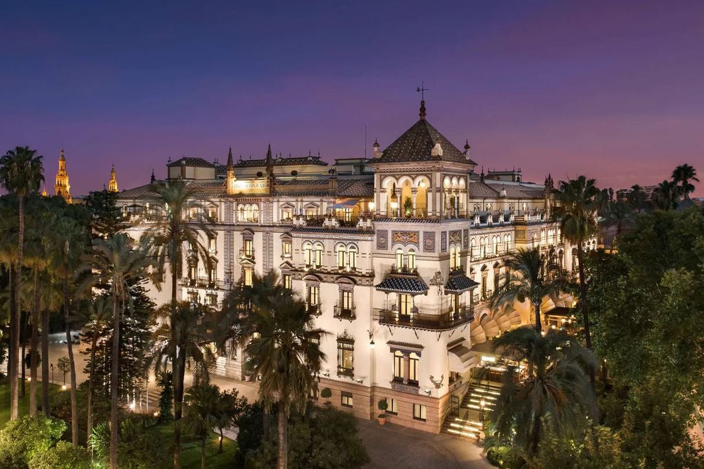 Ornate Moorish-style facade of Hotel Alfonso XIII with arched windows, marble columns, and intricate tilework under blue Spanish sky