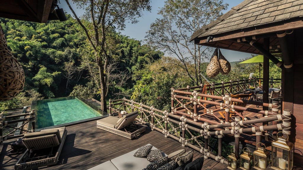 Luxurious raised safari tent nestled in jungle canopy with private deck, overlooking misty Thai mountains at golden hour