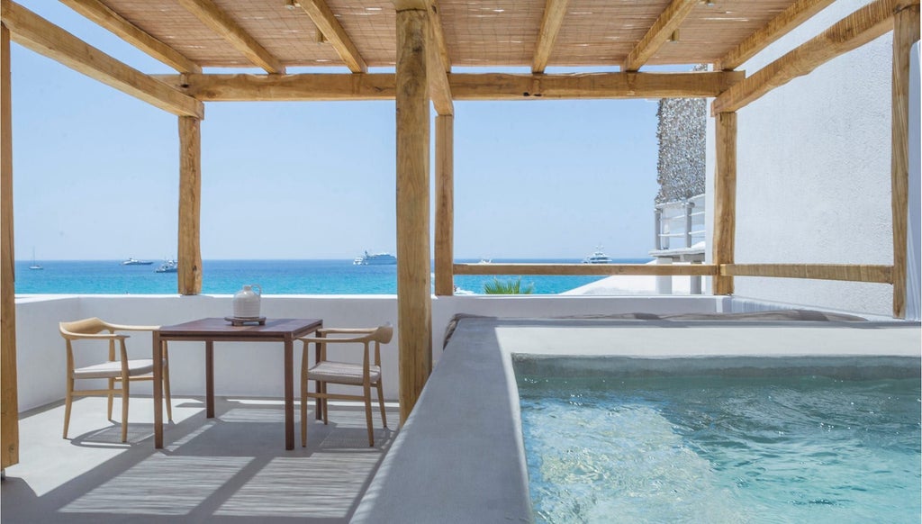 Luxurious white-themed deluxe hotel room with private jacuzzi, panoramic Aegean Sea view, minimalist design, and elegant Mykonos-inspired decor