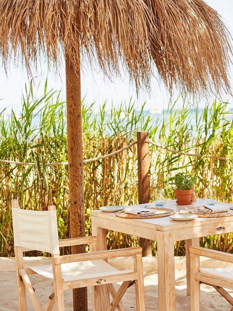 Luxurious white-draped four-poster bed with ocean view, overlooking turquoise waters and sandy beach at stylish seaside resort in Spain