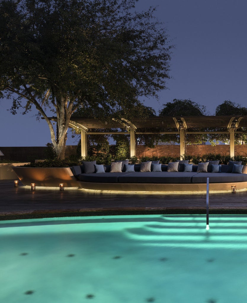 Elegant modern high-rise Four Seasons hotel in downtown Houston with glass facade, luxury entrance canopy and warm exterior lighting at dusk