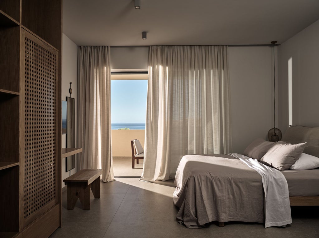 Luxurious white-washed Greek villa bedroom with panoramic Aegean Sea view, elegant minimalist design, and private balcony overlooking scenic coastline