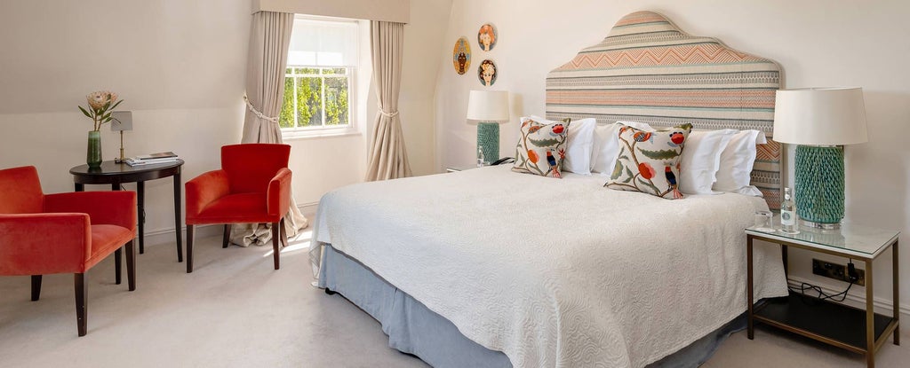 Elegant Georgian-style heritage room with period furnishings, soft neutral tones, ornate four-poster bed, and large sash windows overlooking Bath's historic landscape