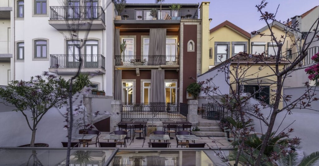 Elegant Portuguese boutique hotel exterior with whitewashed walls, decorative balconies, and manicured gardens framed by palm trees