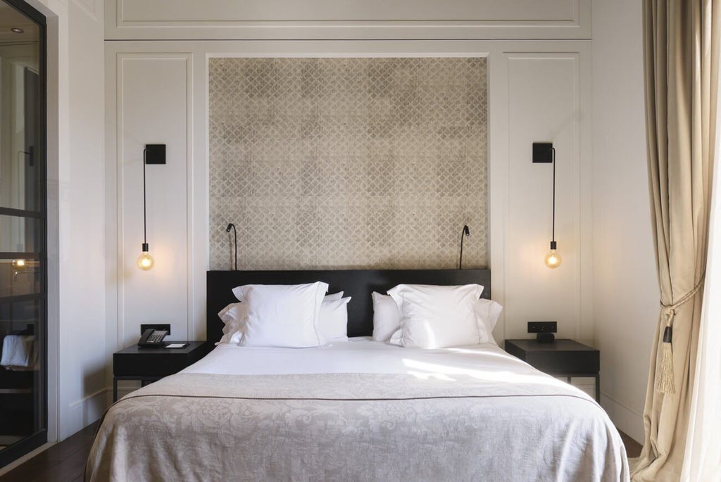 Elegant junior suite with soft neutral tones, minimalist decor, plush king bed, large windows overlooking historic Sant Francesc square in Palma, Mallorca