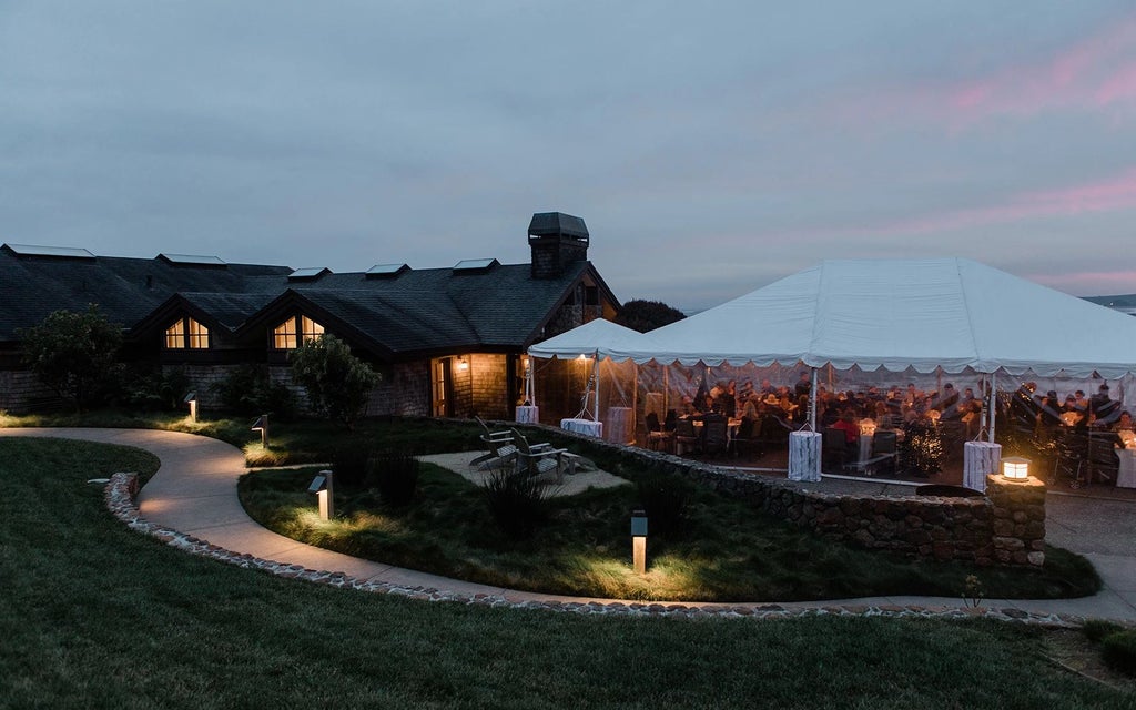 Scenic coastal lodge with modern architecture, expansive windows overlooking Pacific Ocean, featuring elegant wood interiors and luxurious minimalist design