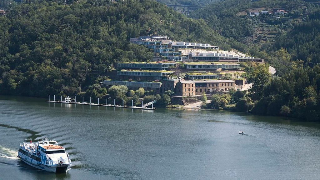 Luxurious infinity pool overlooking Portugal's Douro Valley vineyards with elegant loungers and panoramic river views at sunset