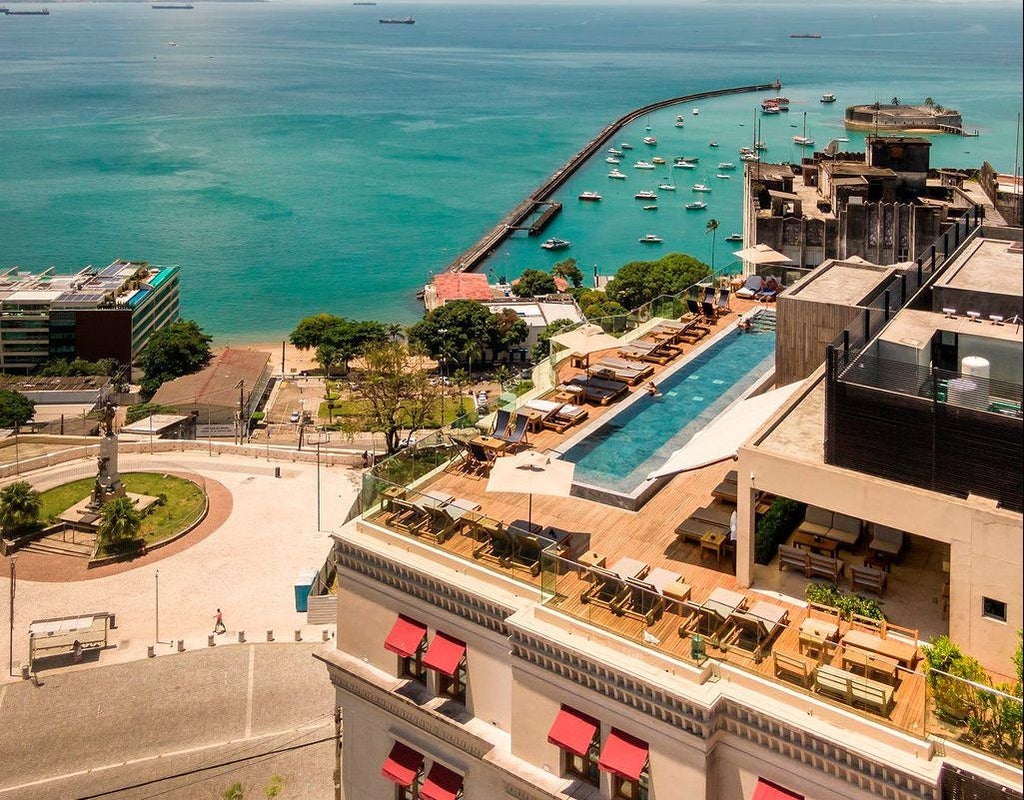 Elegant art deco hotel façade in Salvador, Brazil, with sleek white architecture, palm trees, and tropical sunlight casting sophisticated shadows