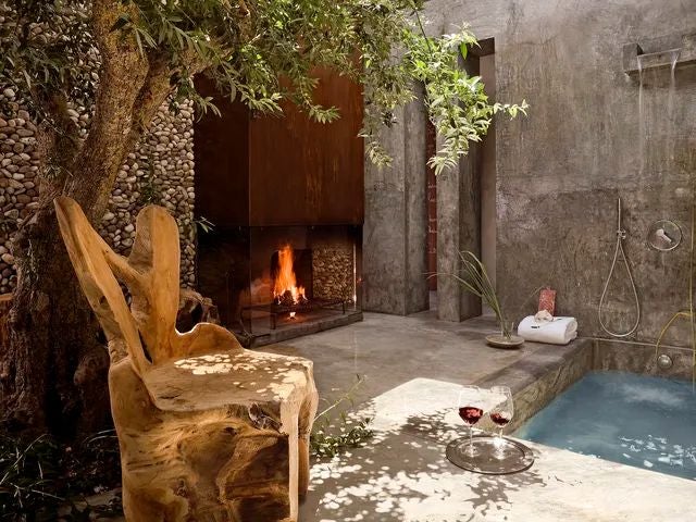 Luxurious rustic-chic hotel room with wooden walls, plush white bedding, and panoramic nature views at Areias do Seixo eco-retreat in Portugal.