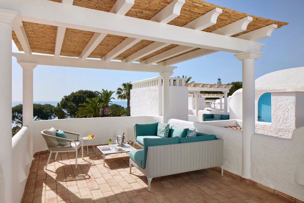 Elegant deluxe hotel room with panoramic ocean view, featuring modern Portuguese design, plush white bedding, and azure Atlantic coastline through large windows