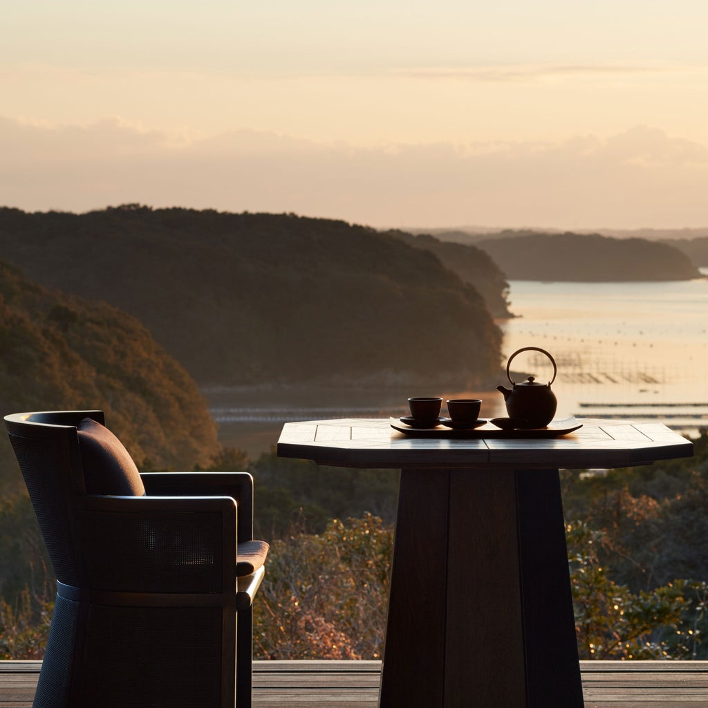 Minimalist Japanese luxury villa with infinity pool overlooking lush mountains and Ago Bay at sunset, featuring zen garden design