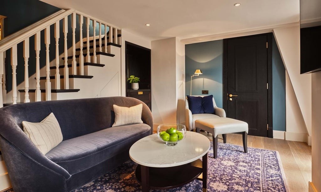 Elegant loft suite with plush furnishings, modern artworks, and expansive windows overlooking a sophisticated London townhouse interior at The Mayfair Townhouse.