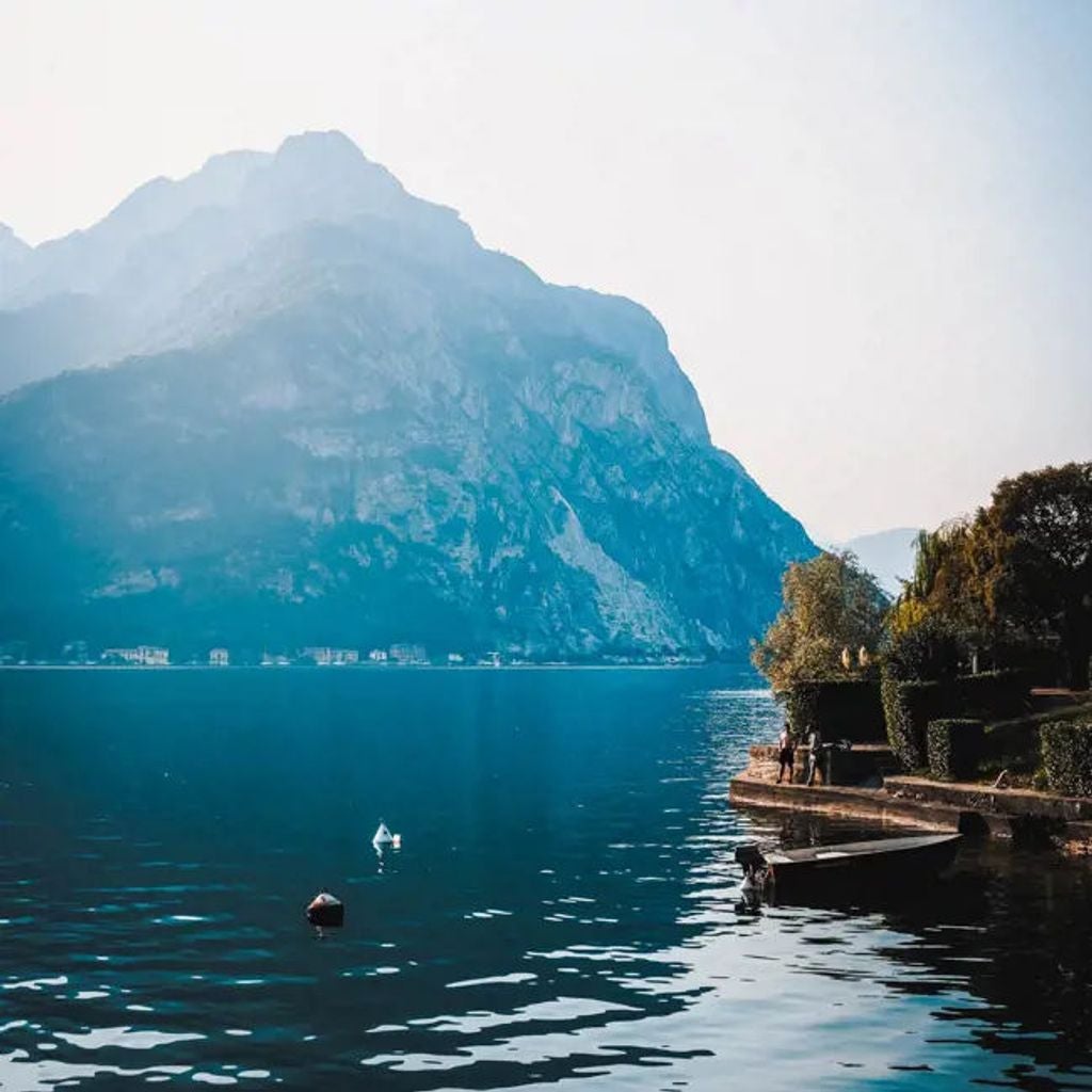 Elegant 19th-century Italian villa with grand terrace overlooking Lake Como, featuring ornate balustrades and manicured gardens at sunset