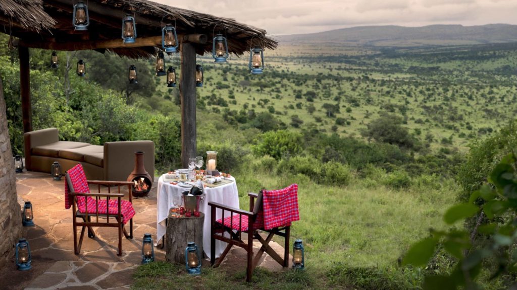 Luxurious safari tent with elegant canopy bed overlooking the Serengeti plains, set against golden savanna at sunset