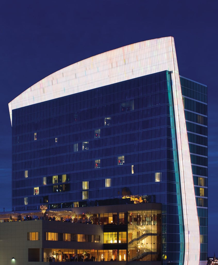 Upscale sky-high glass hotel tower in downtown St. Louis with modern architectural features, reflecting sunset colors in its windows