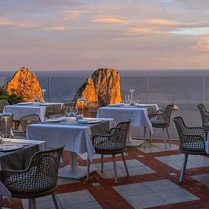 Elegant white Hotel scenset Luna nestled on a picturesque Italian coastal cliff, overlooking azure Mediterranean waters with classic Mediterranean architecture