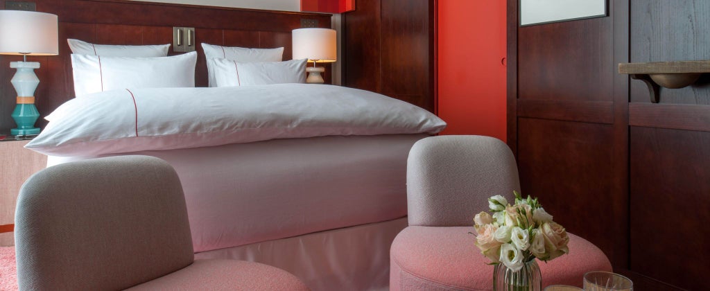 Elegant Parisian hotel room with plush dark gray velvet headboard, soft ambient lighting, and luxurious minimalist design in chic neutral tones