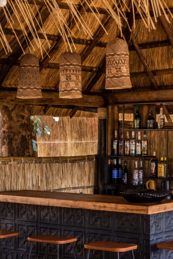 Luxurious safari lodge nestled in Zambia's wilderness, featuring traditional thatched-roof tent with warm wooden decking overlooking pristine riverine landscape