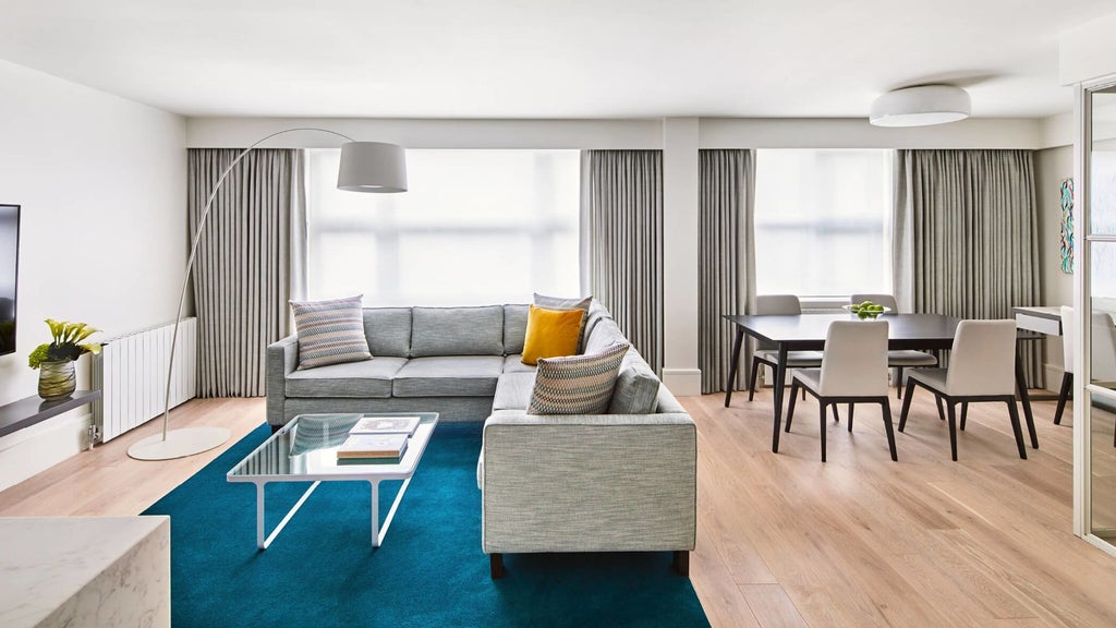 Elegant COMO Suite with plush king bed, contemporary grey decor, floor-to-ceiling windows overlooking London's cityscape, modern luxury hotel room interior