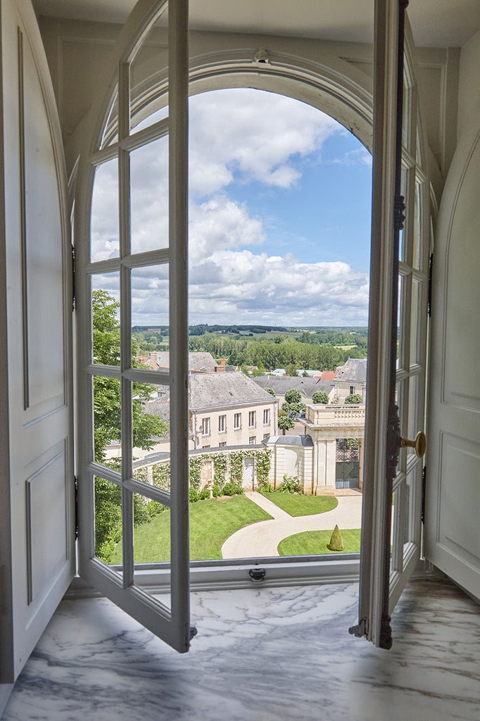 Elegant corner king room with ornate period furnishings, soaring windows, and panoramic French countryside views at Château du Grand-Lucé