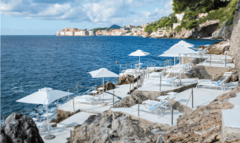 Iconic cliffside Villa Dubrovnik hotel with glass balconies overlooking Adriatic Sea, featuring sleek modern architecture and infinity pool