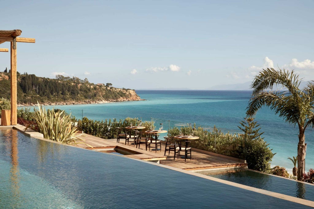 Luxurious infinity pool overlooking azure Ionian Sea, surrounded by sleek white loungers at F Zeen boutique resort in Kefalonia, Greece