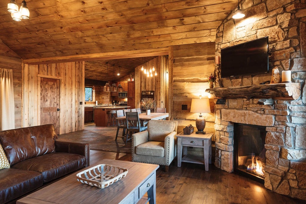 Rustic lodge room with wooden furnishings, plush bedding, and large window overlooking scenic mountain landscape at Scenset Mountain Ranch