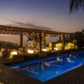 Luxury boutique hotel nestled in historic Santa Teresa neighborhood, Rio de Janeiro, featuring colonial architecture with elegant white facade and tropical palm trees