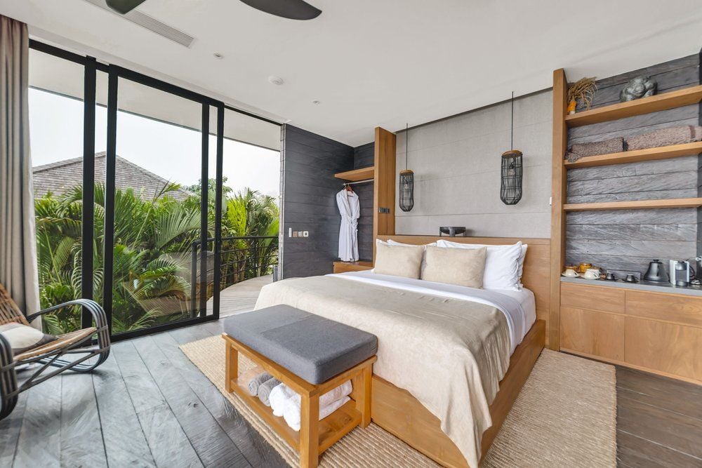 Luxurious wooden studio cabin with floor-to-ceiling windows overlooking lush Balinese jungle, featuring modern furnishings and private balcony