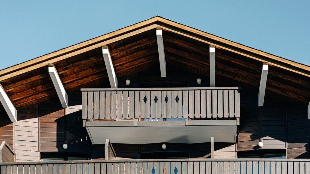 Alpine luxury chalet nestled in Swiss mountains, featuring modern minimalist architecture with expansive glass windows and snow-capped peaks in background